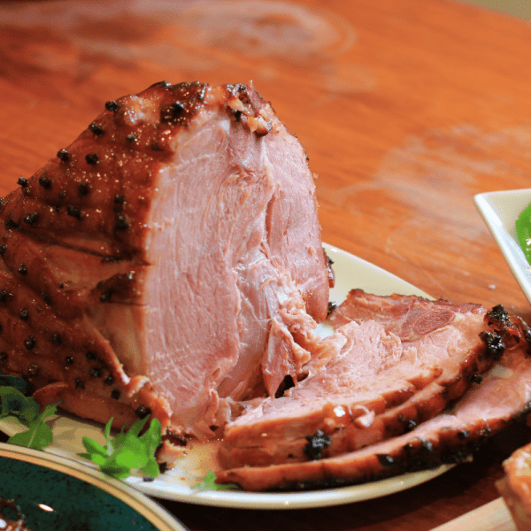 Sliced glazed ham on wooden table